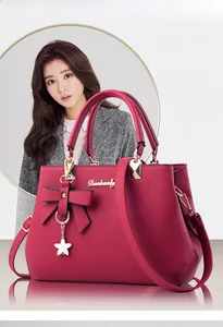 Close-up of wine red cross-grain PU leather handbag with bow and star charm