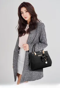 Detail view of black PU leather handbag featuring bow ornament and golden star pendant