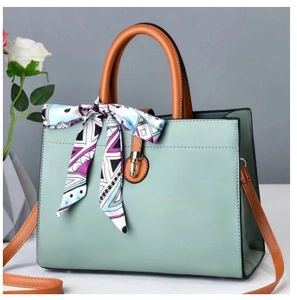 Détail d'un sac à main vert clair avec poignée marron et foulard en soie violet