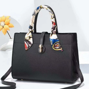 Détail d'un sac à main noir en cuir grainé avec poignée foulard et fermoir doré