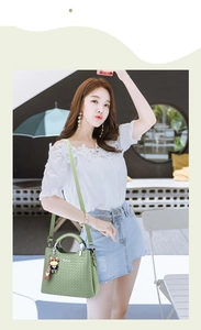 Detail der hellgrünen gewebten Handtasche mit Metallgriff und Kuh-Anhänger an einem Model