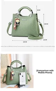 Detailansicht der Größe einer grünen gewebten Ledertasche mit kleinem Kuh-Anhänger
