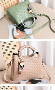 Detail der gewebten PU-Lederhandtasche mit Metalllogo und niedlichem Zeichentrick-Anhänger