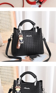 Detail der schwarzen Lederhandtasche mit Flechtmuster, Silberlogo und Anhänger