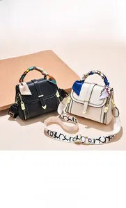 Detail of trendy square bag with silk scarf handle and wide canvas strap with golden heart clasp