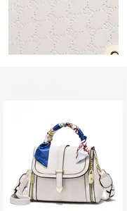 Close-up of white embossed square bag with silk scarf handle and gold heart charm