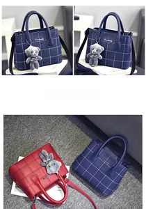Dettaglio di borse in pelle a quadretti blu navy e rossi con ciondolo a forma di orsetto
