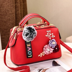 Detail der roten Lederhandtasche mit 3D-Blumenakzenten und Kunstpelz-Anhänger