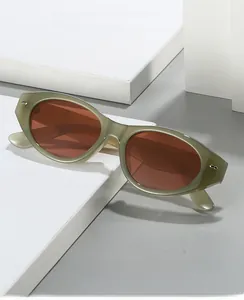 Close-up of olive green cat eye sunglasses with amber lenses on white stone base