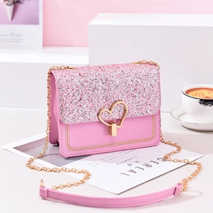 Pink sequined crossbody bag with gold heart lock shown in a stylish cafe setting