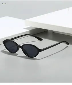 Detail of glossy black oval resin sunglasses frame with dark gray lenses on a white pedestal
