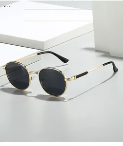 Détail de lunettes de soleil ovales en métal doré avec verres foncés sur un support blanc