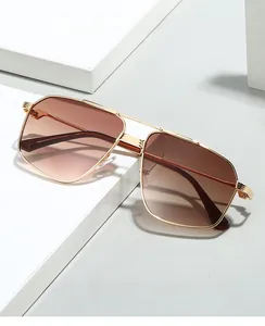 Detail of gold metal aviator sunglasses with brown gradient lenses on geometric display
