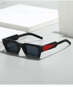 Détail des lunettes de soleil carrées avec accent triangle rouge sur monture mate