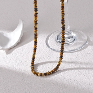 Tiger eye beaded necklace with 14K gold plated discs on a white textured background