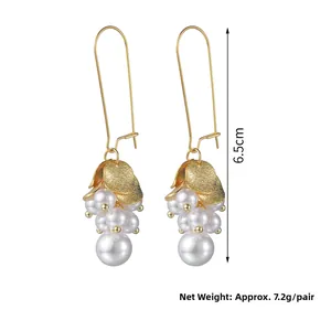 Détail de boucles d'oreilles grappe de perles dorées montrant la mesure de 6,5 cm de long