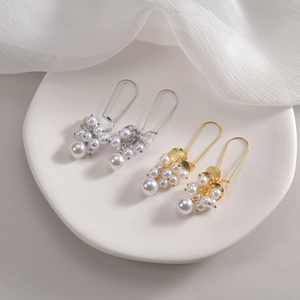 Vue détaillée de boucles d'oreilles martelées dorées et argentées avec perles blanches