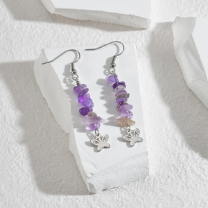 Macro shot of long drop earrings with purple crushed stones and silver butterfly charms