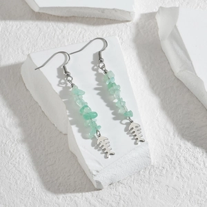 Detail of silver fishbone earrings with light green gravel stones on white stone