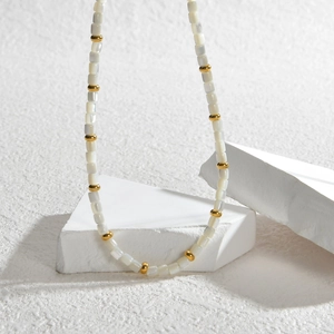 Collier bohème avec perles carrées blanches et accents dorés sur des supports en pierre
