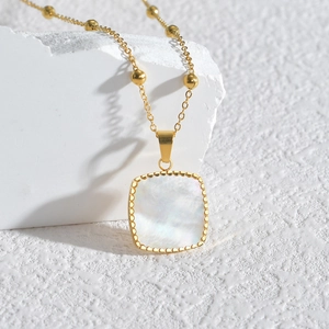 Collier carré doré avec incrustation en nacre et chaîne perlée sur une pierre blanche