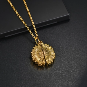 Macro shot of gold sunflower locket necklace with detailed petals on black leather