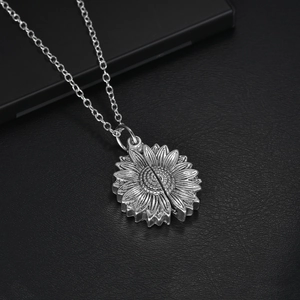 Macro shot of silver sunflower locket necklace on black leather texture background