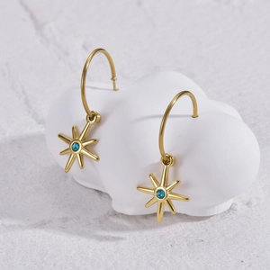 Elegant gold eight-point star earrings with blue zircon on a decorative cloud stand