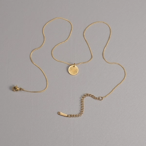 Détail du collier doré avec pendentif soleil, fermoir mousqueton et chaîne d'extension