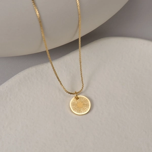 Gros plan détaillé du pendentif rond en acier inoxydable doré 14K à motif rayon