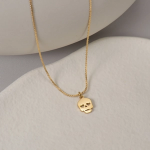 Détail d'un collier plaqué or 14K avec pendentif tête de mort et yeux en cœur sur céramique