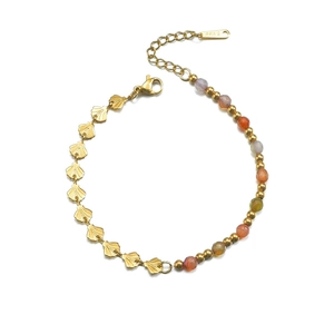 Detailed close-up of gold stainless steel bracelet with shell charms and colored beads