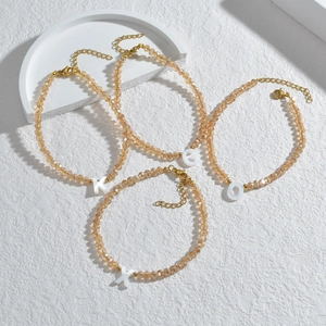 Minimalistische kralenarmbanden met witte letterhangers en gouden sluitingen