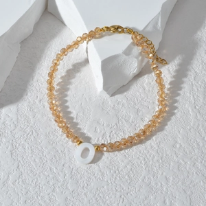 Kralenarmband in champagnegoud met witte letter O hanger en verstelbare ketting