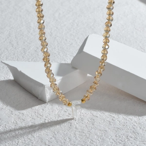 Détail du collier de perles avec cristaux champagne et pendentif lettre F en nacre