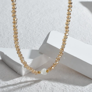Détail du collier de perles en cristal champagne avec pendentif coeur en coquillage