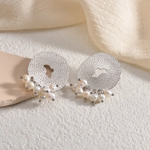 Chic silver hammered oval stud earrings with pearl dangles on a soft textured background