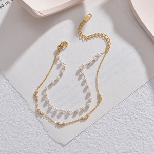 Double-layered golden bracelet featuring delicate white pearls and a sparkling star charm