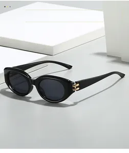 Detail of black oval sunglasses featuring elegant gold double-bar metal hinge accents