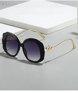 Detail of gold metal temples with double heart decoration on oval fashion sunglasses