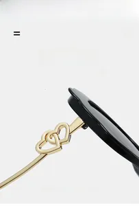 Close-up of golden double heart metal hinges on lightweight black oval sunglasses