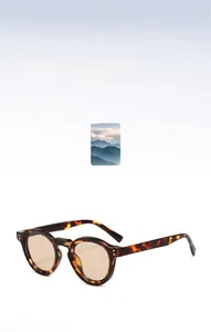 Detail of round tortoiseshell sunglasses with amber lenses and metal frame accents