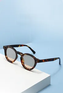 Detail view of round tortoiseshell sunglasses with grey lenses on a white display stand
