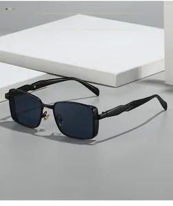 Detail of square metal sunglasses with textured temples on a white stone pedestal