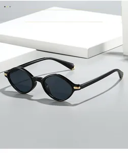 Détail de lunettes de soleil triangulaires noires avec accents dorés et verres sombres