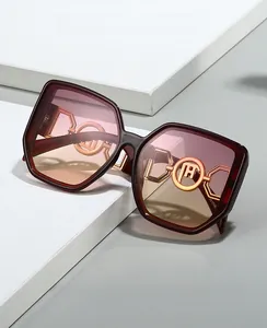 Detail of burgundy oversized sunglasses with gradient lenses and gold circular metal accents