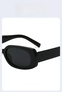 Detailed close-up of glossy black oval frame sunglasses with reinforced hinge design