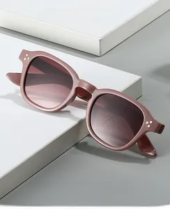 Dettaglio di occhiali da sole ovali rosa con lenti sfumate marroni e borchie