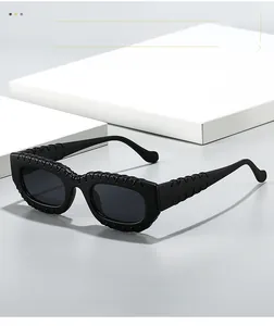 Détail de lunettes de soleil carrées noires avec texture tressée sur une monture mate élégante
