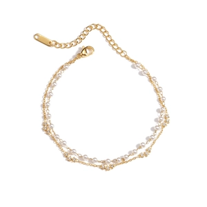 Double-layered gold chain bracelet with pearls and crystal star charms on white background